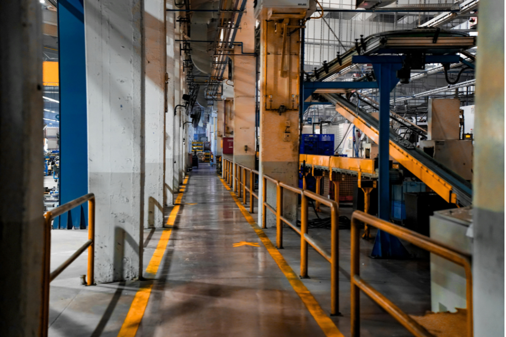A long hallway featuring yellow lines and various machinery, illustrating OSHA swing gate compliance requirements.