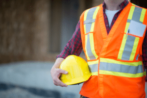A construction worker holding a hard hat, emphasizing the importance of safety equipment on the job site.