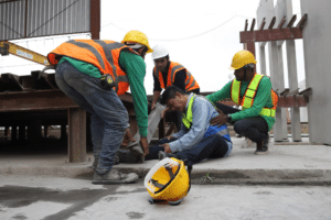 Construction workers are engaged in a workplace emergency, collaborating on a construction site to address the situation.