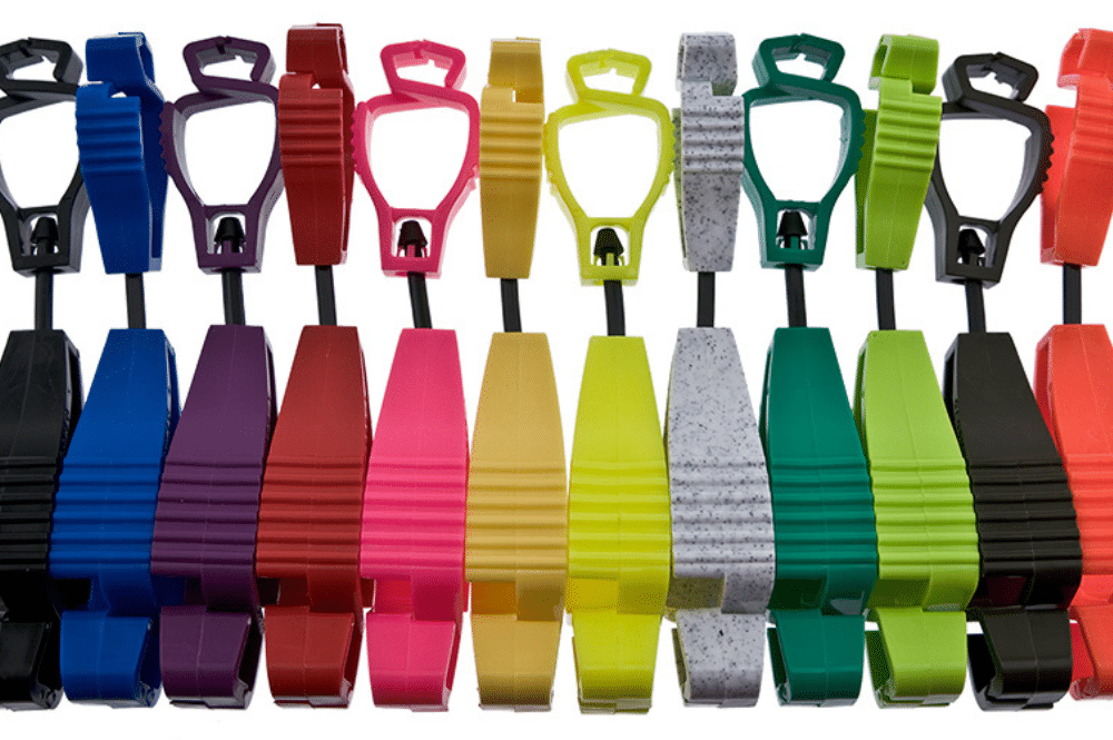 A collection of colorful plastic safety glove clips for workers arranged on a white background.