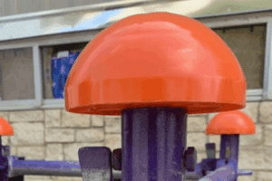 A metal pole in a construction setting, covered with a Scaff Hat™ scaffolding cap for workplace safety.