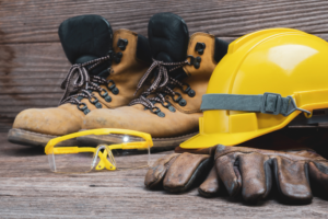 A pair of hard hats, gloves, and goggles, showcasing the need and advantages of plastic safety equipment for protection on job sites.